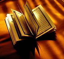 A paper Quran opened halfwise on top of a brown cloth