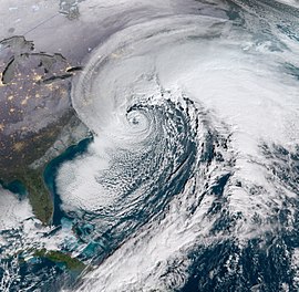 Satellite image of a sprawling cloud structure centered horizontally. Cuba is visible on the bottom-left of the image while the eastern United States is visible on the left.