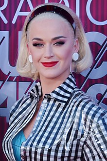 Katy Perry, a woman smiling and looking towards a camera.